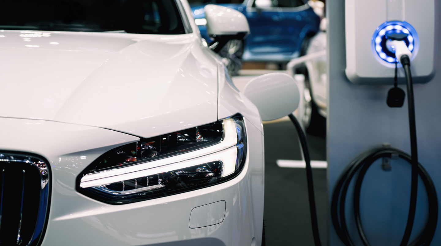 Véhicule électrique branché à une borne de recharge dans un parking résidentiel urbain français, environnement contemporain
